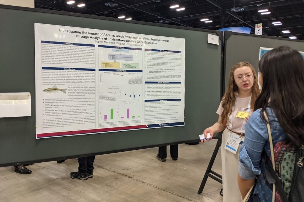 A student presents her research poster at a conference.